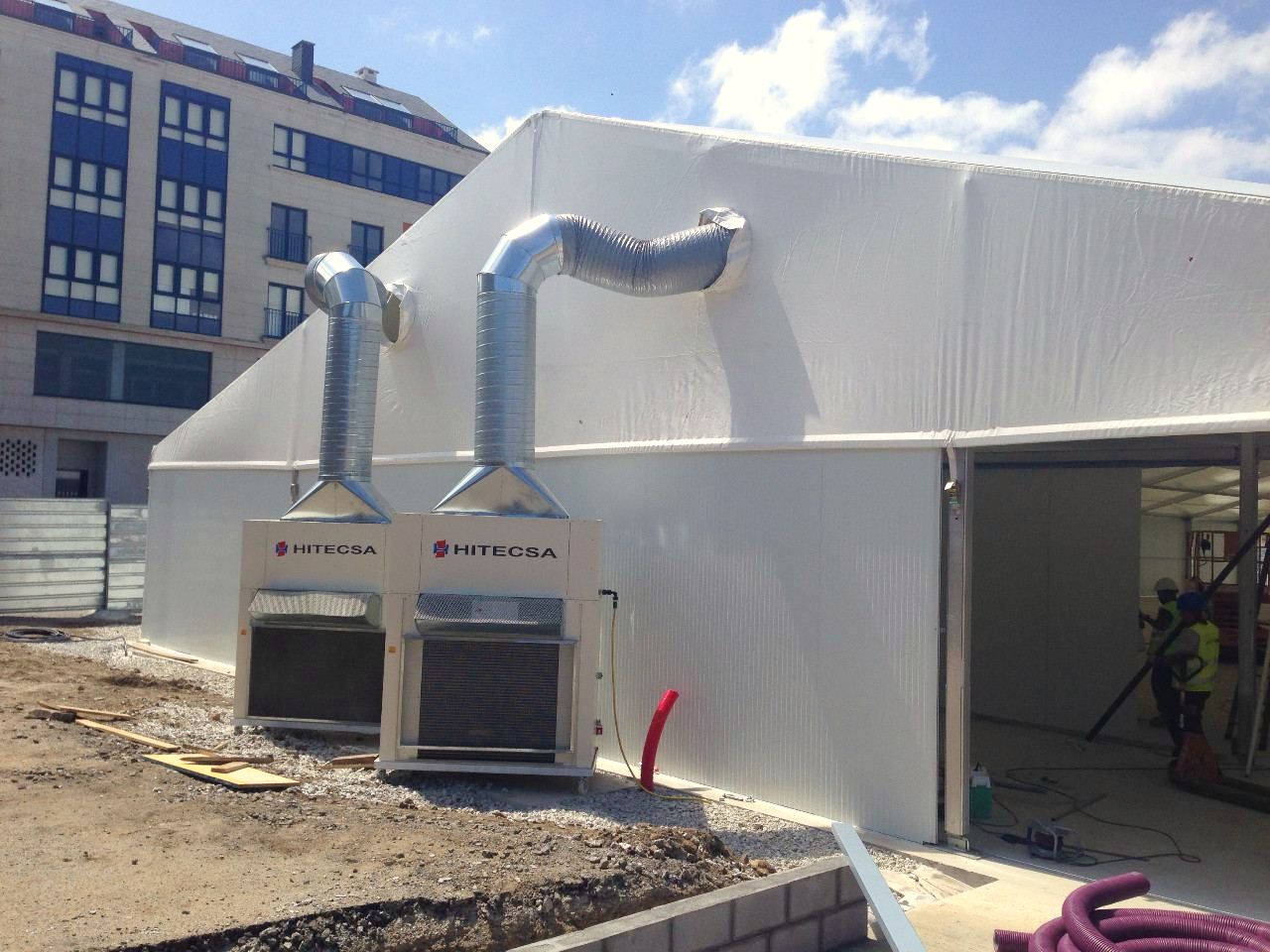 Equipos compactos de aire acondicionado con conductos y cableado junto a una carpa