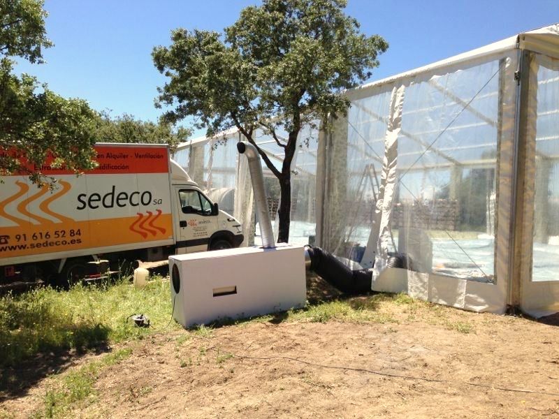 Furgoneta de SEDECO junto a una carpa con un generador de aire caliente y conductos